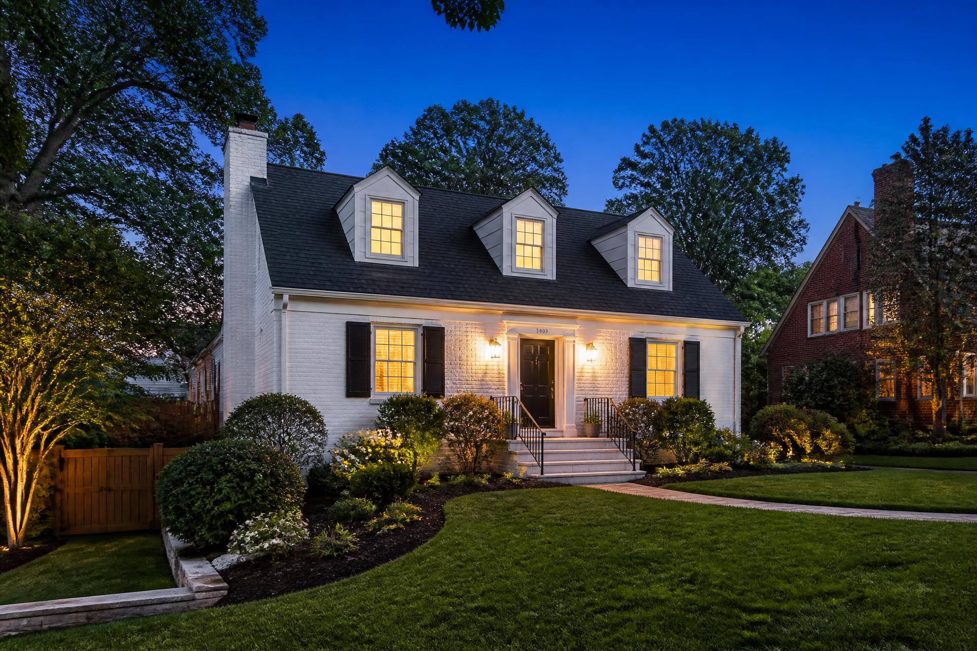Twilight exterior of the white Cape Cod home at 6522 Cavalier Drive in Alexandria, Virginia